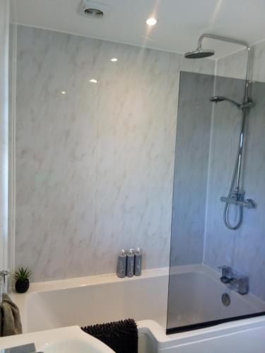 a bathroom with a shower and a tub with a sink at 'Serenity in Somerset ' Self Catering House Rental Near Chard , Accomodation for Contract Workers only in Chardstock