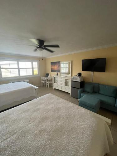 a bedroom with a bed and a couch and a tv at Coral Sands Inn in Ormond Beach