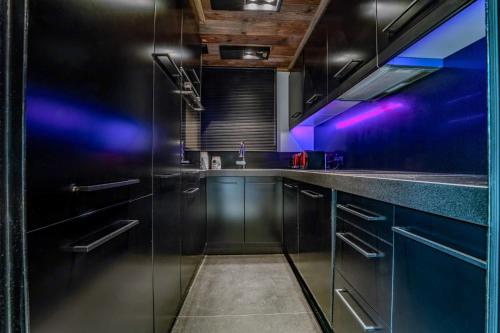 une cuisine avec des armoires noires et des lumières violettes dans l'établissement Cosy & Modern Apt in Megeve 8 Guests View 3BR, à Megève