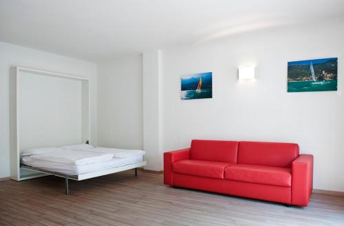 a red couch and a bed in a room at Villa Treccani Apartments in Malcesine