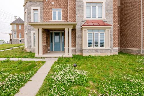 a brick house with white flowers in the yard at The Residence, Your comfort is our culture in Oakville