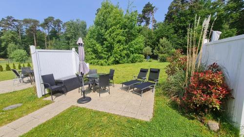 a patio with chairs and an umbrella in a yard at Ferienwohnung Ostsee Graal-Müritz Küstenwald in Gelbensande