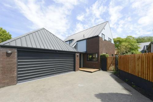 a brick house with a metal garage door at Airport Retreat 4 Bedrooms 8 Guests in Christchurch