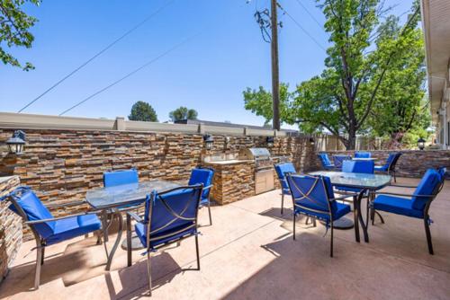 a patio with blue chairs and tables and a stone wall at Comfort Inn Grand Junction I-70 in Grand Junction