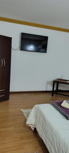 a bedroom with a bed and a tv on the wall at Hostal La Caleta in Salta