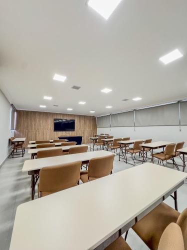 an empty classroom with tables and chairs and a screen at Ilha Porchat Hotel in São Vicente