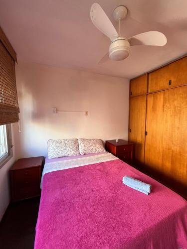 a bedroom with a pink bed with a ceiling fan at Flat na Orla do Guaíba com Piscina e Camareira in Porto Alegre
