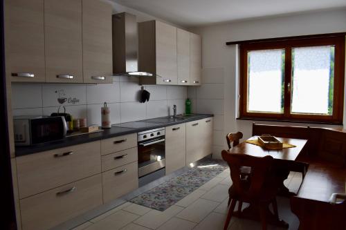 a kitchen with white cabinets and a table in it at Appartamento sole in Isone