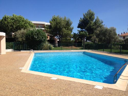une piscine avec de l'eau bleue dans une cour dans l'établissement Studio en rez de jardin dans résidence calme avec piscine, à Juan-les-Pins
