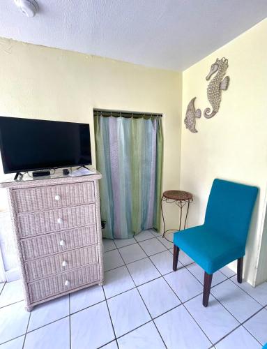 a living room with a tv and a blue chair at Coconut Cove Resort & Marina in Islamorada