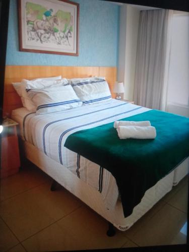 een bed met een groene deken en twee handdoeken erop bij Hotel glamuroso in Guarulhos
