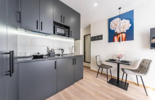 a kitchen with black cabinets and a table and chairs at Новий Люкс, ЖК Варшавський, Виговського 4012, 5 хв Ретровіль, Вишгород in Kyiv
