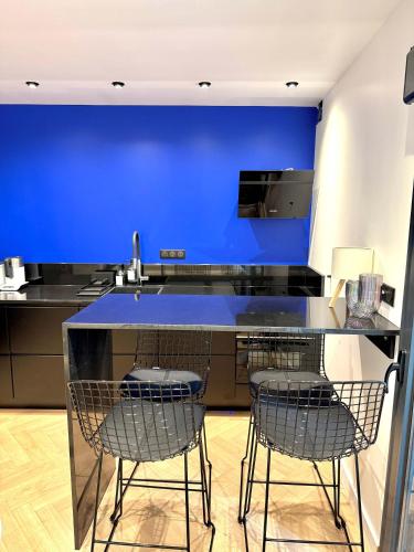 une cuisine bleue avec trois chaises et un comptoir dans l'établissement Sur les traces de Cyrano Duplex, à Bergerac