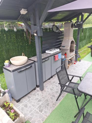 an outdoor kitchen with a grill and a table and a chair at Igloo Rasnov in Râşnov