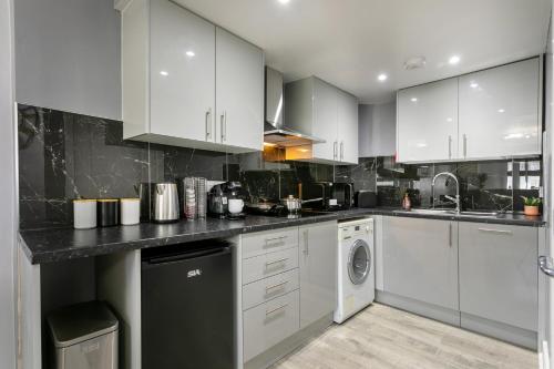 a kitchen with white cabinets and a washer and dryer at Luxury Retreat in the Heart of Leicester City Centre! in Leicester