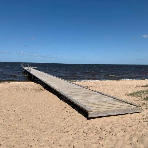 a wooden pier on a beach next to the water at FF1006 Autentisk Feriebolig i Hemmet med adgang til pool in Hemmet