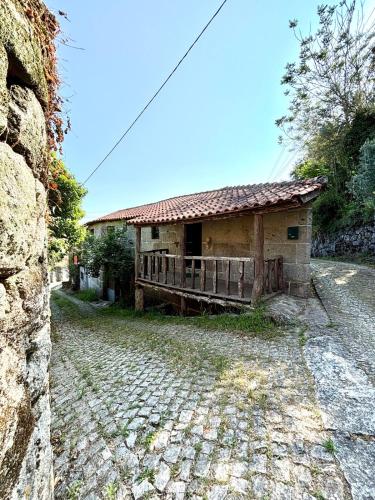 a building on a cobblestone street next to a house at Casa do Arte - Peaceful Retreat with a Pool near Guimarães in São Torcato