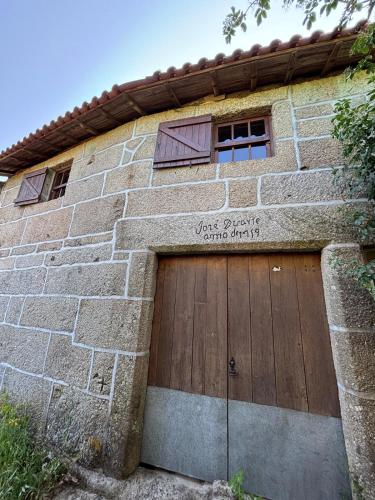 a brick building with a wooden garage door at Casa do Arte - Peaceful Retreat with a Pool near Guimarães in São Torcato