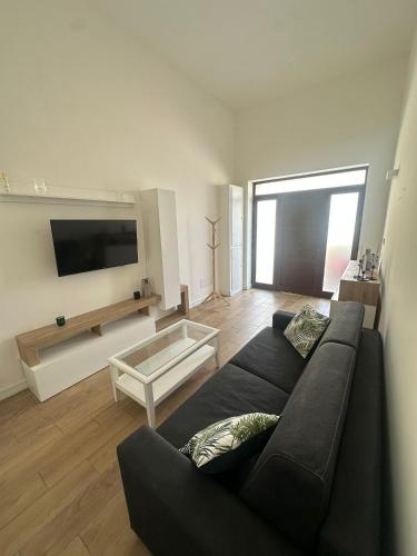 Una sala de estar con un sofá negro y un televisor. en Modesti Tower, en Mesagne