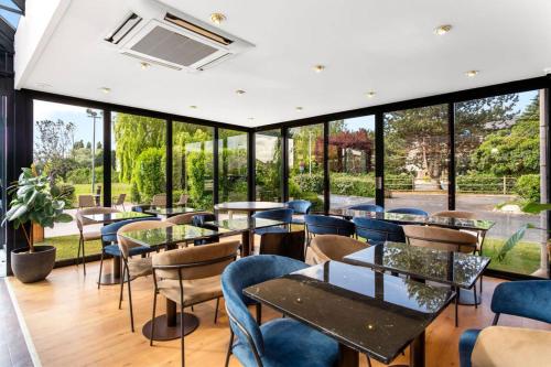 a restaurant with tables and chairs and windows at Kyriad Deauville - St Arnoult in Deauville