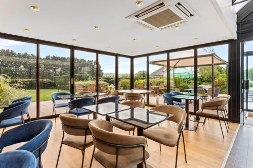 a dining room with tables and chairs and windows at Kyriad Deauville - St Arnoult in Deauville