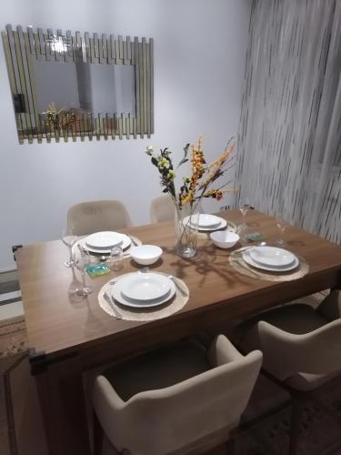 a wooden table with white plates and chairs and a mirror at Lac 2 البحيرة in Tunis