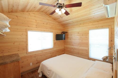 1 dormitorio con 1 cama y ventilador de techo en Lake Conroe Two-Bedroom Cabin 13, en Willis