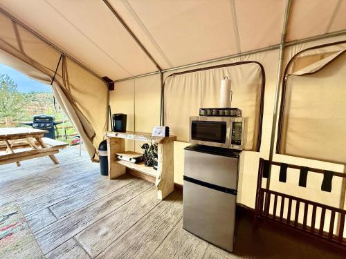 a tent with a kitchen and a microwave in it at Glamping Tent #10 with Heat AC and Private Bath in Orderville