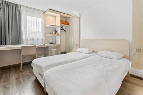 a hotel room with two beds and a desk and a kitchen at Kyriad Deauville - St Arnoult in Deauville