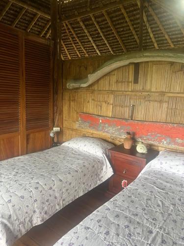 a bedroom with two beds in a thatched room at Casa Amare Bolivar Zapotal Island 14pax 7hab in Muisne