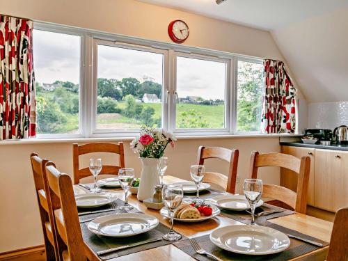 a dining room table with chairs and a clock on the wall at 3 Bed in Crediton WAIE4 in Zeal Monachorum