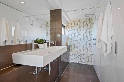 a bathroom with a white sink and a shower at La Mer at Alex - easy walk to beach in Alexandra Headland