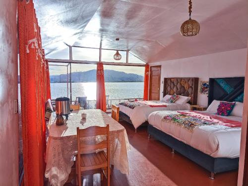 プーノにあるTiticaca Kontiki Eco Lodge Peruのベッド2台とテーブルと窓のある寝室