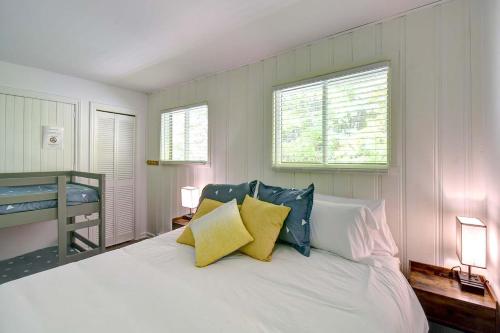 a bedroom with a white bed with yellow and blue pillows at Waterfront - Chalet des Becassines in Nominingue
