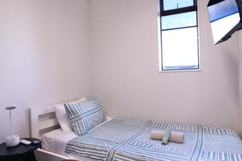a bed in a white room with a window at Onehunga Suites in Auckland