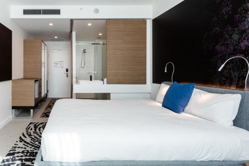 a bedroom with a large white bed and a bathroom at Novotel Brisbane South Bank in Brisbane