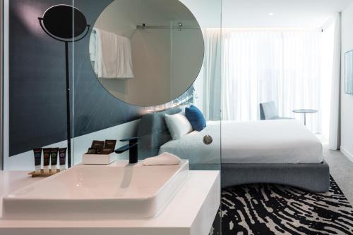 a bedroom with a bed and a sink and a mirror at Novotel Brisbane South Bank in Brisbane