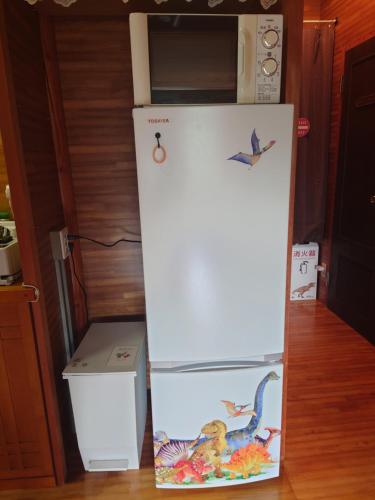 a white refrigerator with birds on it in a kitchen at 恐竜博物館まで車10分バーベキュー機材無料貸出勝山ファミリーログハウス今日のおうち in Katsuyama