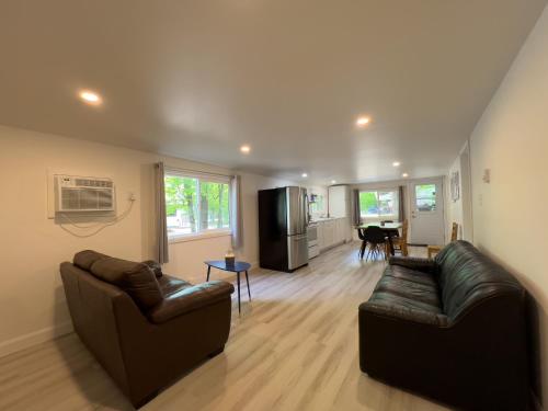 a living room with two leather couches and a kitchen at Camping Chalets Lac St-Augustin in Quebec City