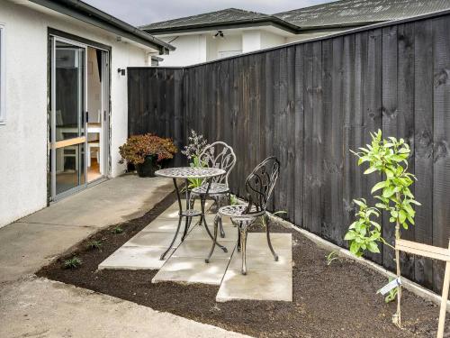 a patio with two chairs and a table and a fence at Cabbage Tree Corner in Napier