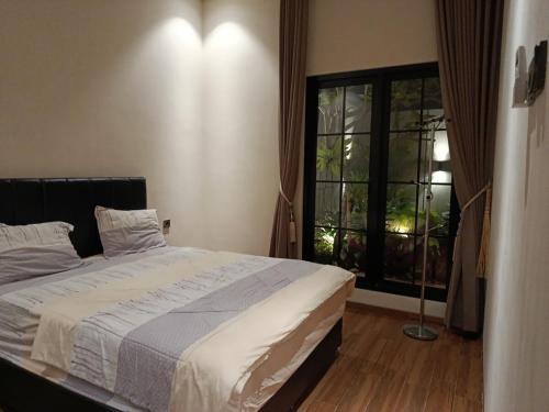 ein Schlafzimmer mit einem Bett und einem großen Fenster in der Unterkunft Villa Tasnim Syariah Landungsari in 