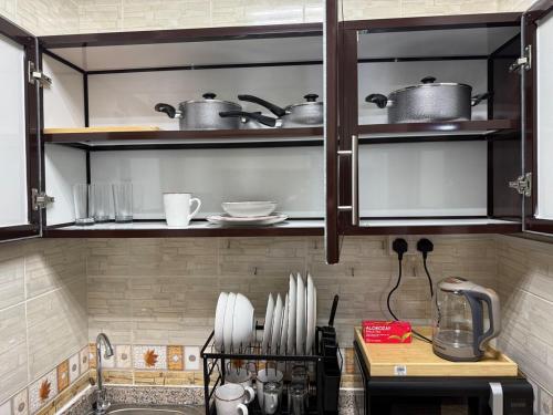 a kitchen with some pots and pans on shelves at Brand new - Stylish Studio Near to Yas & Airport in Abu Dhabi