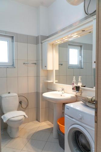 a bathroom with a toilet sink and a washing machine at Parid Appartments in Sarandë