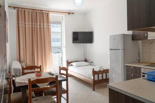 a kitchen with a living room with a table and a refrigerator at Parid Appartments in Sarandë