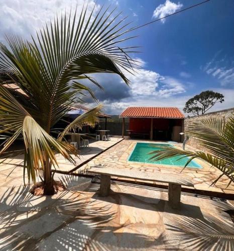 a palm tree and a swimming pool with a building at Chacara Linhares in Pirenópolis