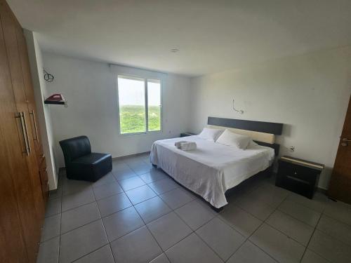 a bedroom with a bed and a chair and a window at Beachfront apartments Cancun in Cancún