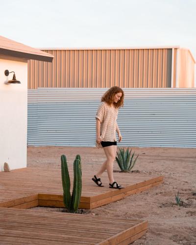 a woman walking on a wooden platform next to a cactus at Hi Desert Pool Club in Landers