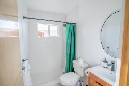 a bathroom with a toilet and a green shower curtain at Hi Desert Pool Club in Landers