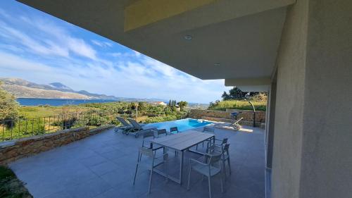 a patio with a table and chairs and a swimming pool at Arsinoe Villa in Kouvaláta