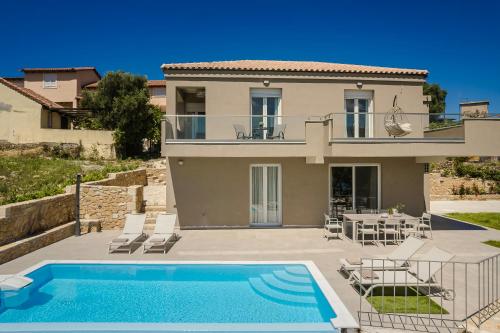 a villa with a swimming pool in front of a house at Arsinoe Villa in Kouvaláta